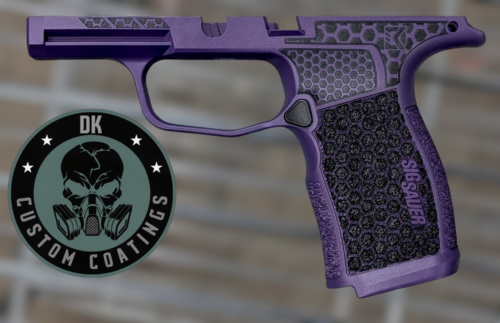 Close-up of a purple handgun frame with a honeycomb textured grip and a circular logo overlapping the lower left corner of the image.