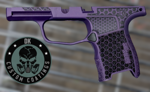 Purple handgun with a hexagonal grip pattern and a circular logo patch overlapping the lower left corner.
